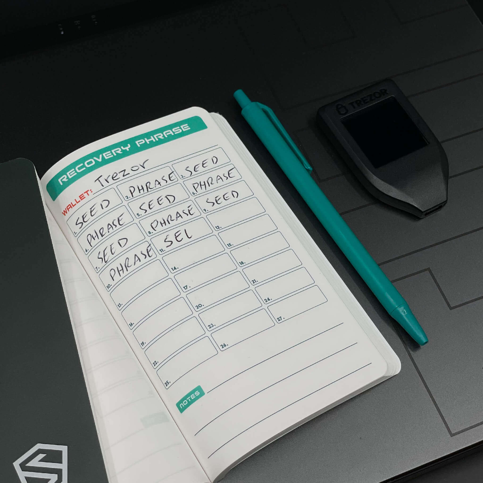Shieldfolio Stonebook laying on office desk laptop with written hardware wallet seed phrase